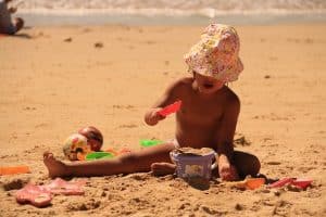 ילד משחק בחול בים